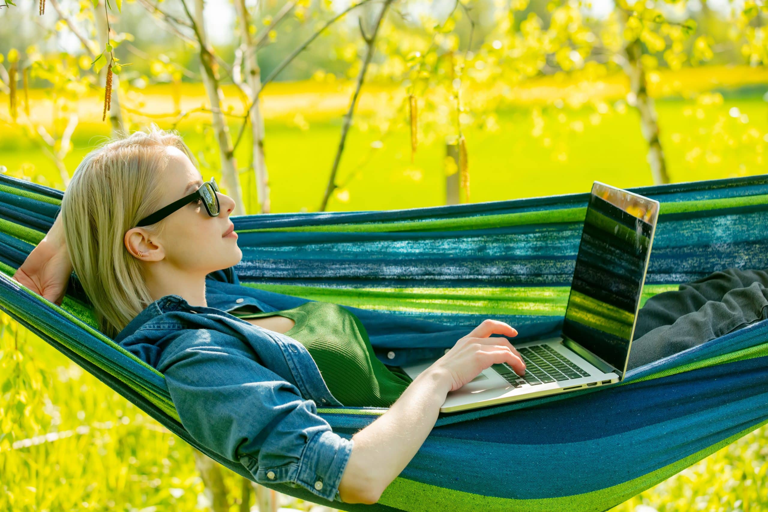 Nainen riippumatossa kannettavant tietokoneen kanssa